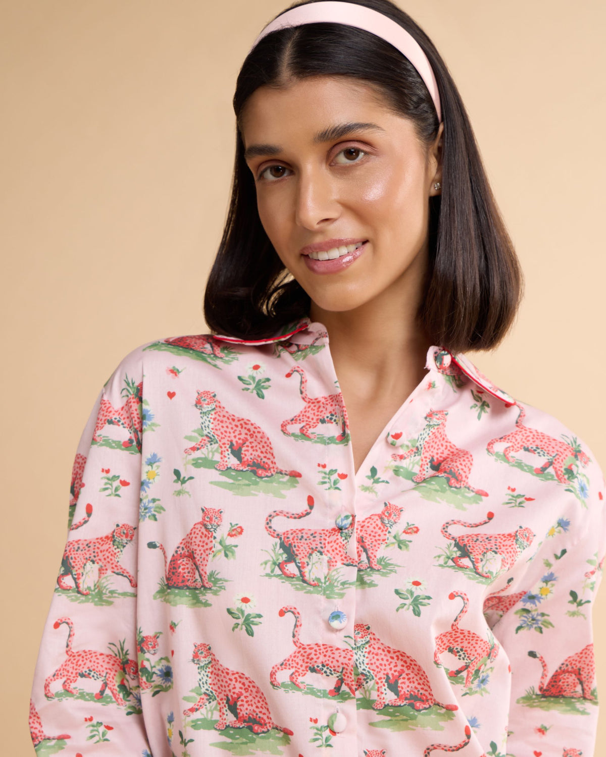 Close-up of the Layla Pink pyjama shirt showing the rounded collar, coral piping and storybook leopard print