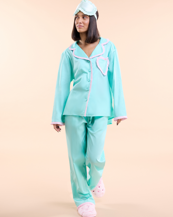 Model wearing the Dolce Menta Pyjama, a mint green cotton long pyjama set with peach trim and heart-shaped pocket, by Love Letters x