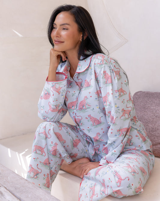 Layla Blue Long PJ Set – close-up of model seated with chin resting on hand, wearing pale blue long-sleeve pyjama shirt with pink leopard and floral print and pink piping collar detail