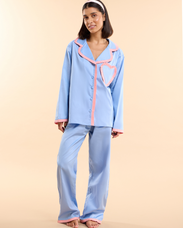 Model wearing the Dolce Sorbetto Pyjama, a pale blue cotton long pyjama set with apricot trim and heart-shaped pocket, by Love Letters x